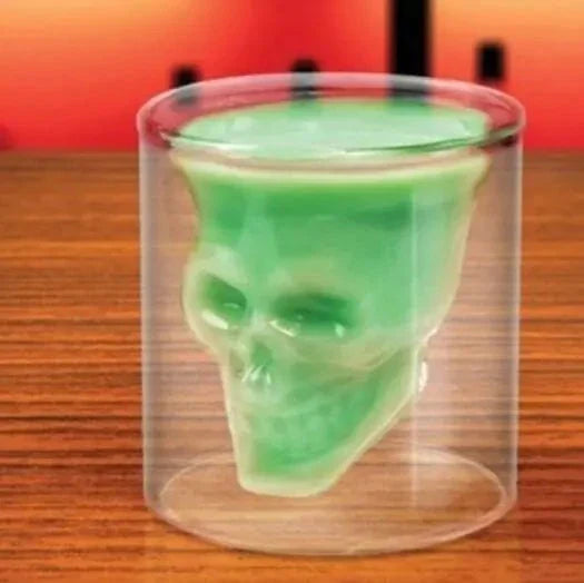 Skull Head Crystal Wine Glass with green liquid on a wooden table.