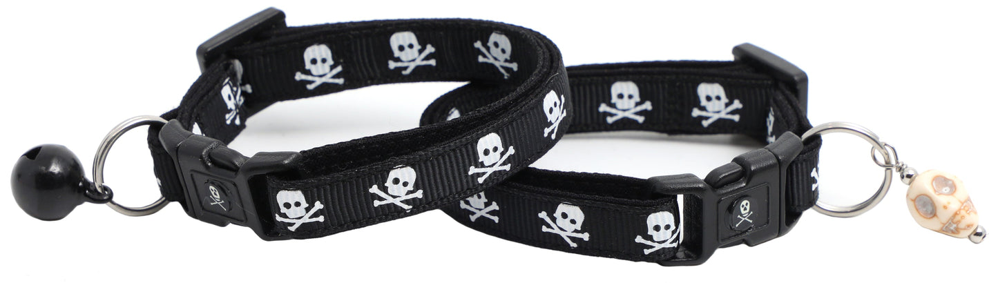 Skulls and crossbones design on black cat collar with bell and charm.
