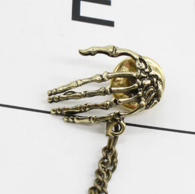 Bold Alloy Skull Claw Pin with Tassel, Electroplated Finish in Gold, Luxurious Statement Accessory.