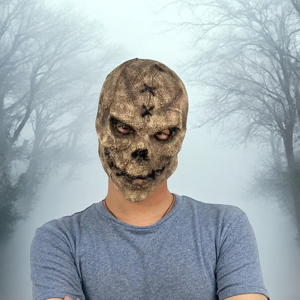 Brown stitched horror skull mask worn by person in foggy forest background