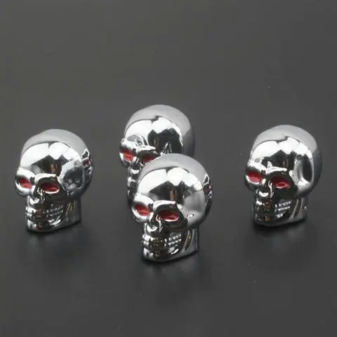 Skull style valve caps with ghost head design in stainless steel, held in hand.