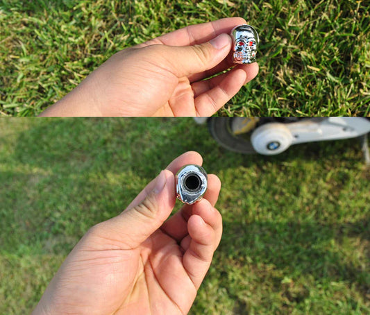 Skull style valve caps with ghost head design in stainless steel, held in hand.