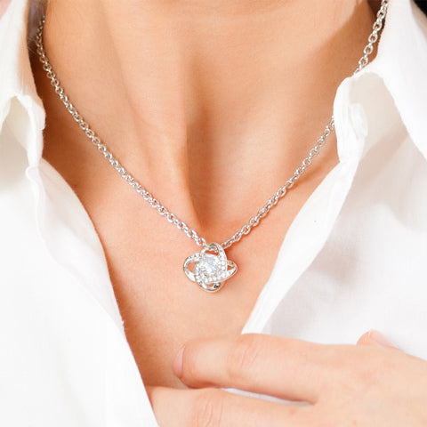 Close-up of a person wearing a Love Knot Necklace with a cubic zirconia pendant on a silver chain
