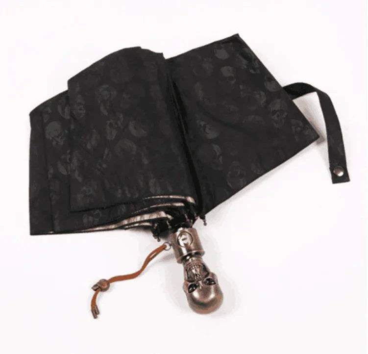 Folding umbrella with skull design, durable impact cloth, sleek black finish.